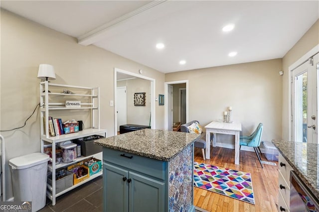 kitchen featuring a center island, stone countertops, dark hardwood / wood-style flooring, french doors, and beamed ceiling