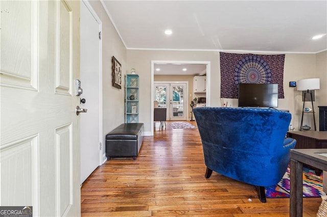 living room with french doors, ornamental molding, and light wood-type flooring