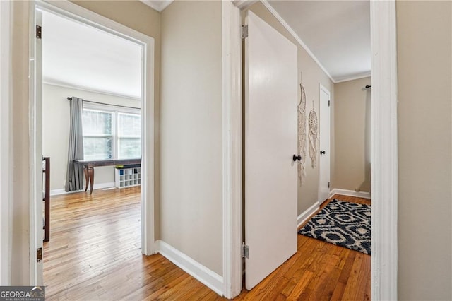 hallway featuring ornamental molding and light wood-type flooring