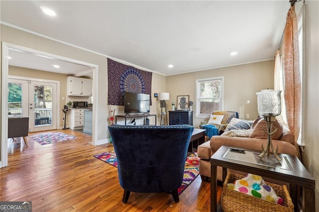 living room featuring crown molding, light hardwood / wood-style floors, and french doors