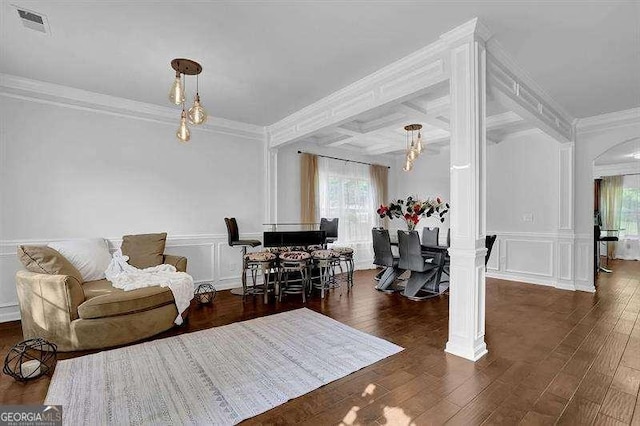 living room featuring beam ceiling, ornamental molding, dark wood-type flooring, and decorative columns