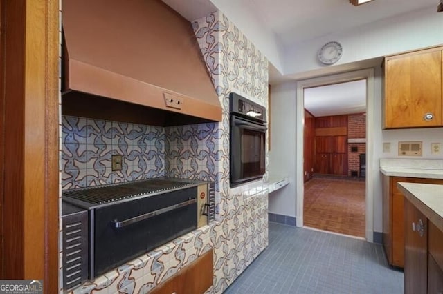 kitchen with tasteful backsplash, oven, dark tile patterned floors, and wall chimney exhaust hood