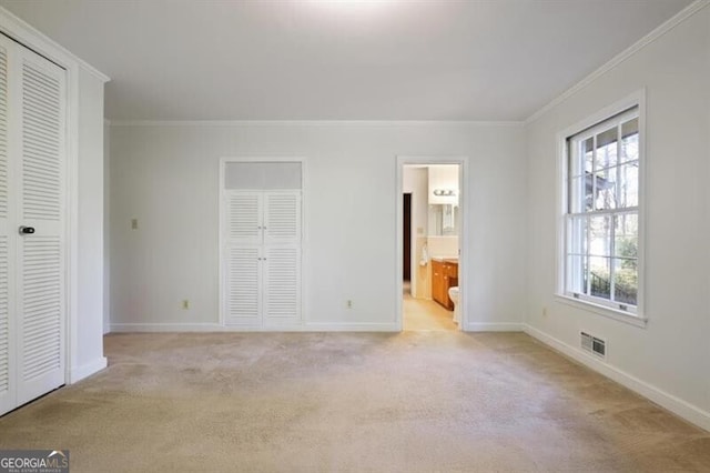 unfurnished bedroom with light carpet, ensuite bathroom, and ornamental molding