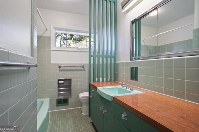 full bathroom with tile patterned floors, vanity, tile walls, and toilet