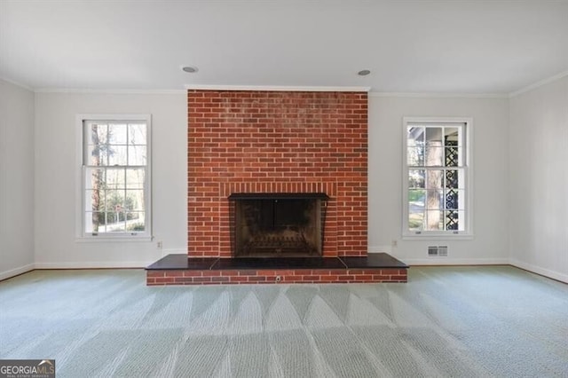 unfurnished living room with a fireplace, carpet floors, and crown molding