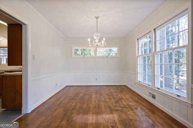 unfurnished dining area featuring a chandelier, dark hardwood / wood-style floors, and ornamental molding