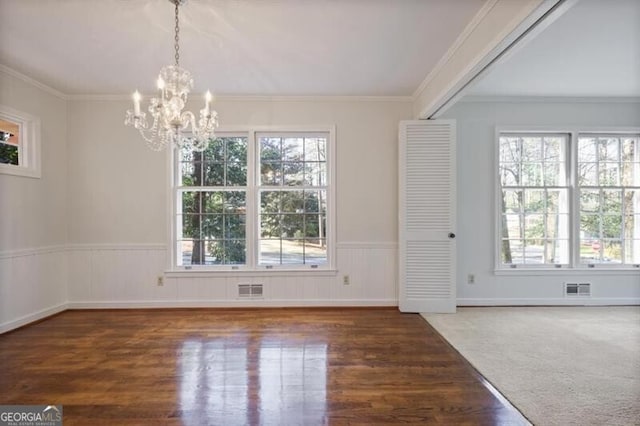 unfurnished dining area with dark hardwood / wood-style floors, crown molding, and a notable chandelier