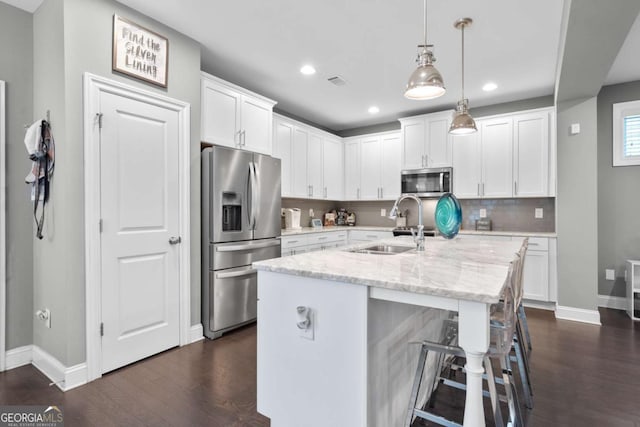 kitchen featuring white cabinetry, pendant lighting, light stone counters, and appliances with stainless steel finishes