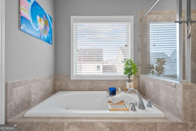 bathroom featuring tiled bath and a wealth of natural light