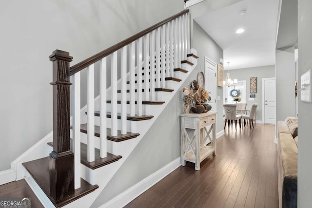 staircase with hardwood / wood-style floors and a notable chandelier