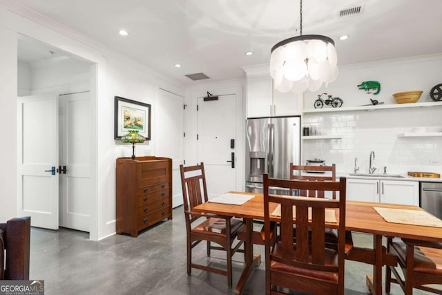 dining room featuring crown molding, sink, and a notable chandelier