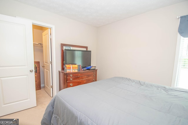 bedroom featuring a walk in closet and light carpet