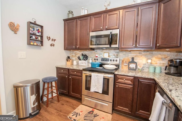 kitchen with decorative backsplash, appliances with stainless steel finishes, light hardwood / wood-style flooring, and light stone counters