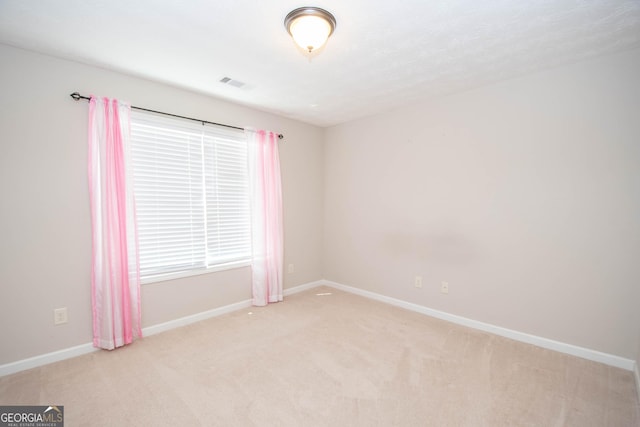 unfurnished room with baseboards, visible vents, and light colored carpet