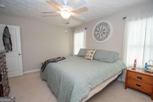 carpeted bedroom featuring ceiling fan and a textured ceiling