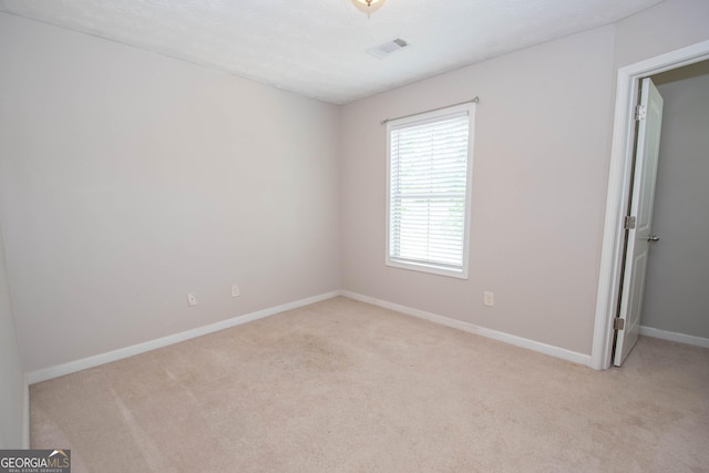 spare room featuring visible vents, baseboards, and light carpet