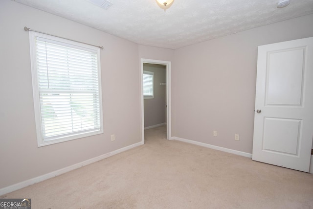 unfurnished bedroom with a textured ceiling, baseboards, and light carpet