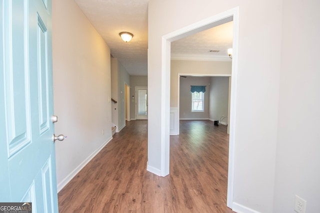 corridor with baseboards, wood finished floors, and ornamental molding