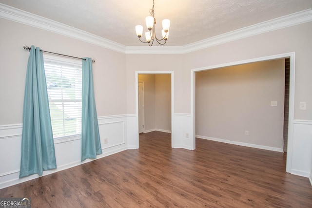 unfurnished dining area featuring an inviting chandelier, crown molding, a wainscoted wall, and wood finished floors
