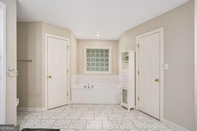 bathroom featuring tile patterned floors, a bathtub, toilet, and a textured ceiling