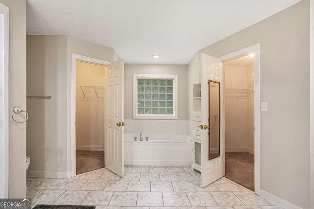 bathroom featuring tile patterned floors, toilet, a tub to relax in, and a textured ceiling