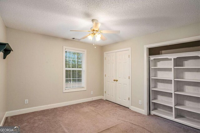 unfurnished bedroom featuring ceiling fan, carpet, and a textured ceiling