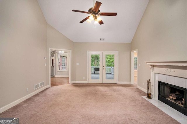 unfurnished living room with ceiling fan, french doors, high vaulted ceiling, light colored carpet, and a fireplace