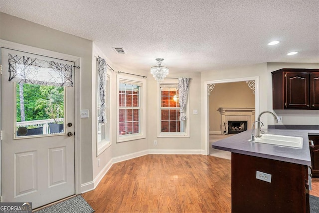 interior space featuring a textured ceiling, light hardwood / wood-style flooring, a tiled fireplace, and sink