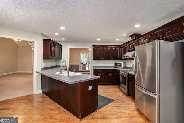 kitchen with a breakfast bar, sink, appliances with stainless steel finishes, dark brown cabinets, and kitchen peninsula