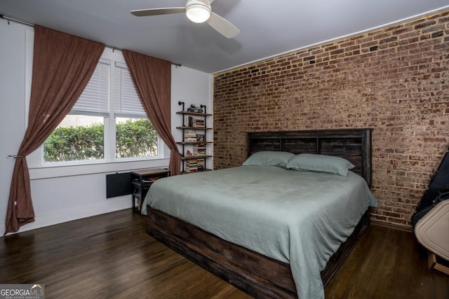 bedroom with ceiling fan, dark hardwood / wood-style flooring, and brick wall