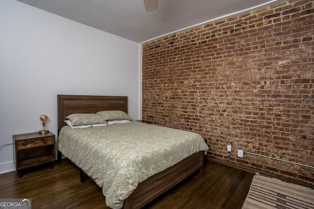 bedroom featuring ceiling fan, dark hardwood / wood-style flooring, and brick wall