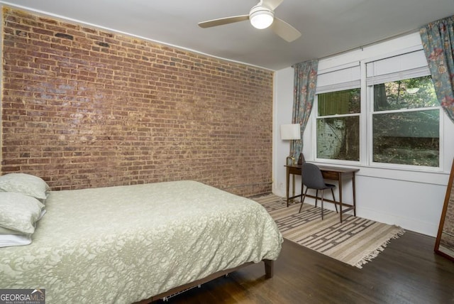 bedroom featuring hardwood / wood-style flooring, ceiling fan, and brick wall