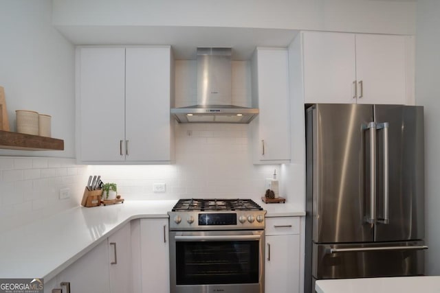 kitchen featuring backsplash, white cabinets, wall chimney range hood, and premium appliances