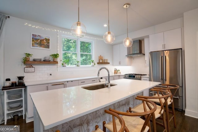 kitchen with pendant lighting, white cabinets, sink, wall chimney exhaust hood, and appliances with stainless steel finishes