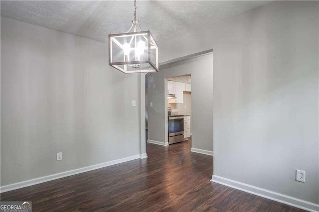 unfurnished dining area featuring a chandelier, a textured ceiling, and dark hardwood / wood-style floors