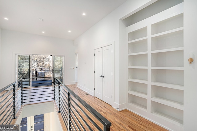 corridor with built in shelves and hardwood / wood-style flooring