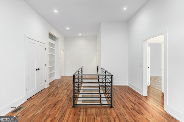 hall with wood-type flooring and built in shelves