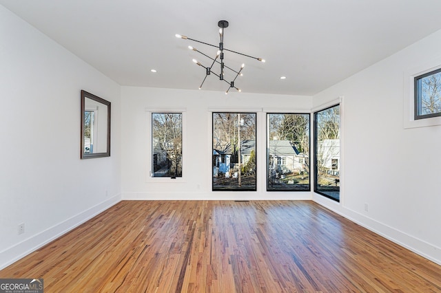 spare room with a chandelier and hardwood / wood-style floors