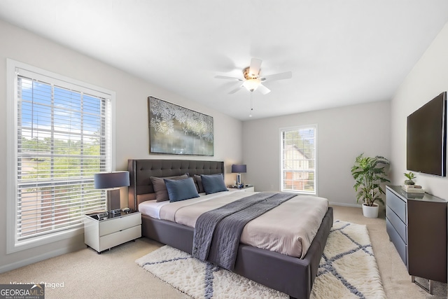 bedroom with ceiling fan, light carpet, and multiple windows