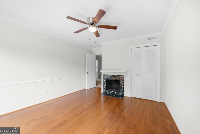 unfurnished living room with a high end fireplace, wood-type flooring, ceiling fan, and ornamental molding