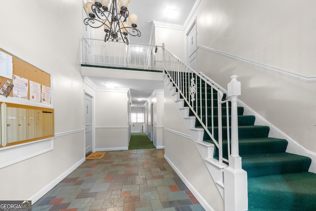 stairs with a chandelier, a high ceiling, and ornamental molding