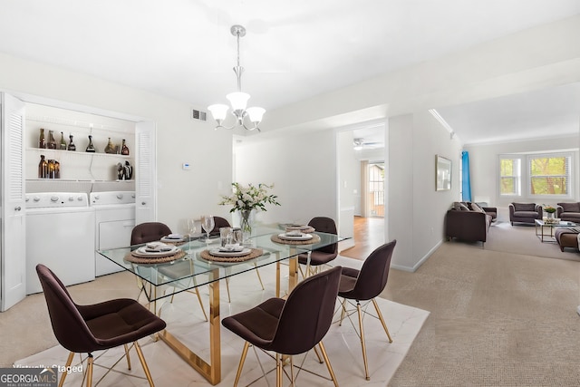 carpeted dining area with ceiling fan with notable chandelier, built in shelves, washing machine and dryer, and a wealth of natural light