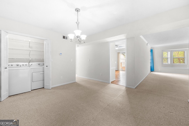 empty room featuring ceiling fan with notable chandelier, light carpet, washing machine and dryer, and a healthy amount of sunlight