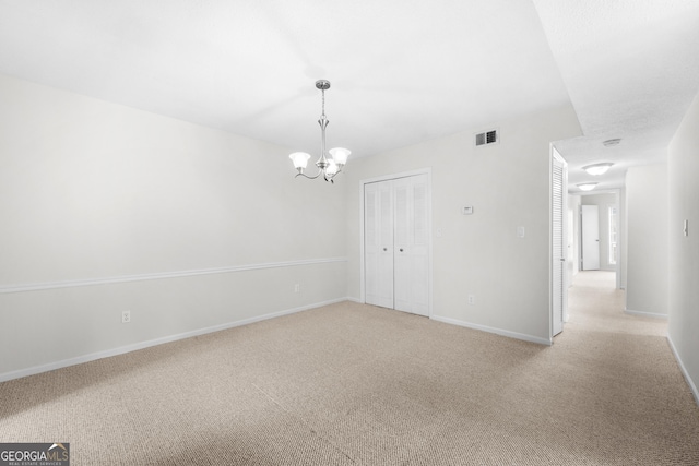 carpeted empty room with a notable chandelier