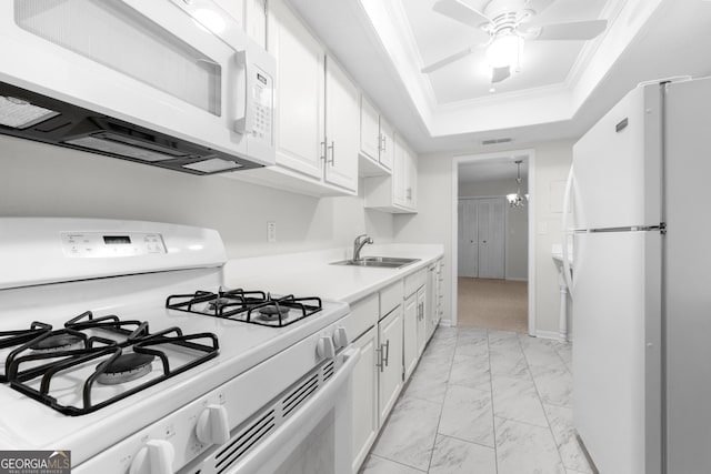 kitchen with sink, white appliances, a tray ceiling, white cabinets, and ornamental molding