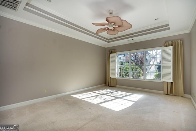 spare room with a tray ceiling, ceiling fan, light colored carpet, and ornamental molding