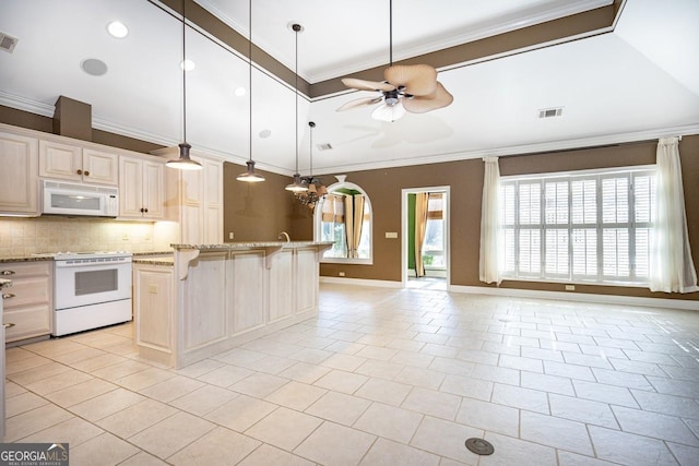 kitchen featuring ceiling fan, a center island, light stone counters, white appliances, and a breakfast bar area