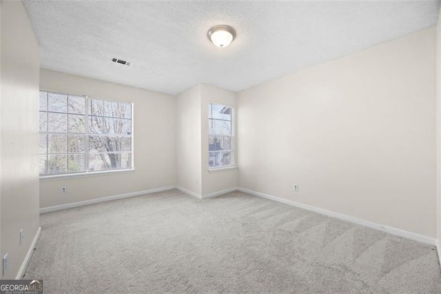 carpeted empty room featuring a textured ceiling