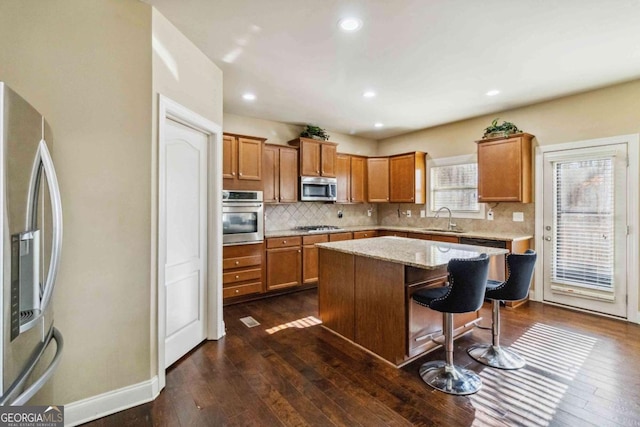 kitchen with sink, a breakfast bar, backsplash, stainless steel appliances, and a kitchen island