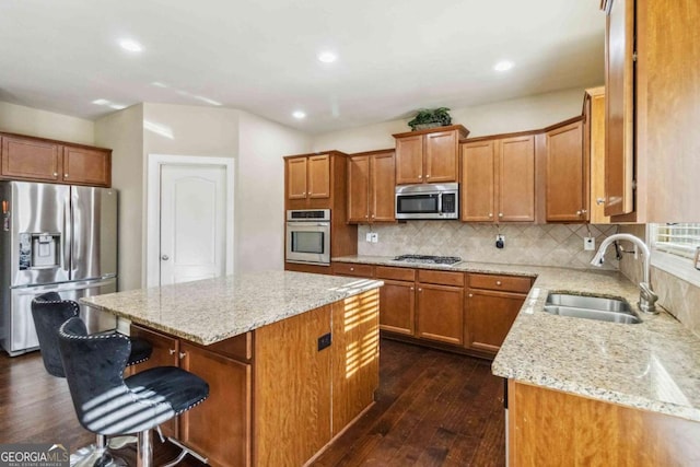 kitchen featuring a kitchen bar, sink, a center island, stainless steel appliances, and decorative backsplash